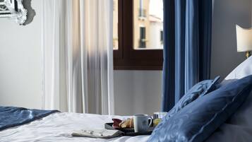 A neatly made bed with a tray of breakfast items, including a croissant, a cup, and a glass of orange juice.