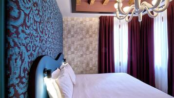 Una camera d'albergo con carta da parati decorata, un letto grande, un lampadario e una finestra con tende.