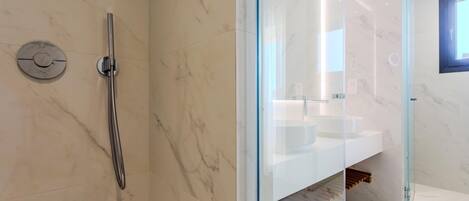 A modern bathroom with a glass-enclosed shower, a white sink, and marble flooring.