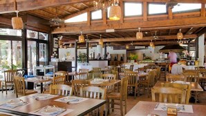 Un restaurante con interiores de madera, varias mesas de comedor y lámparas colgantes.