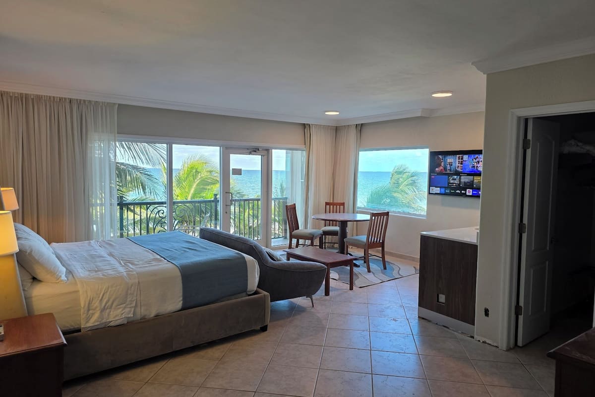 Ein Hotelzimmer mit Bett, Schreibtisch, Stuhl, Fernseher und einem Balkon mit Meerblick.