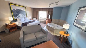 Habitación de hotel con cama, sofá, mesa y baño con bañera y ducha.