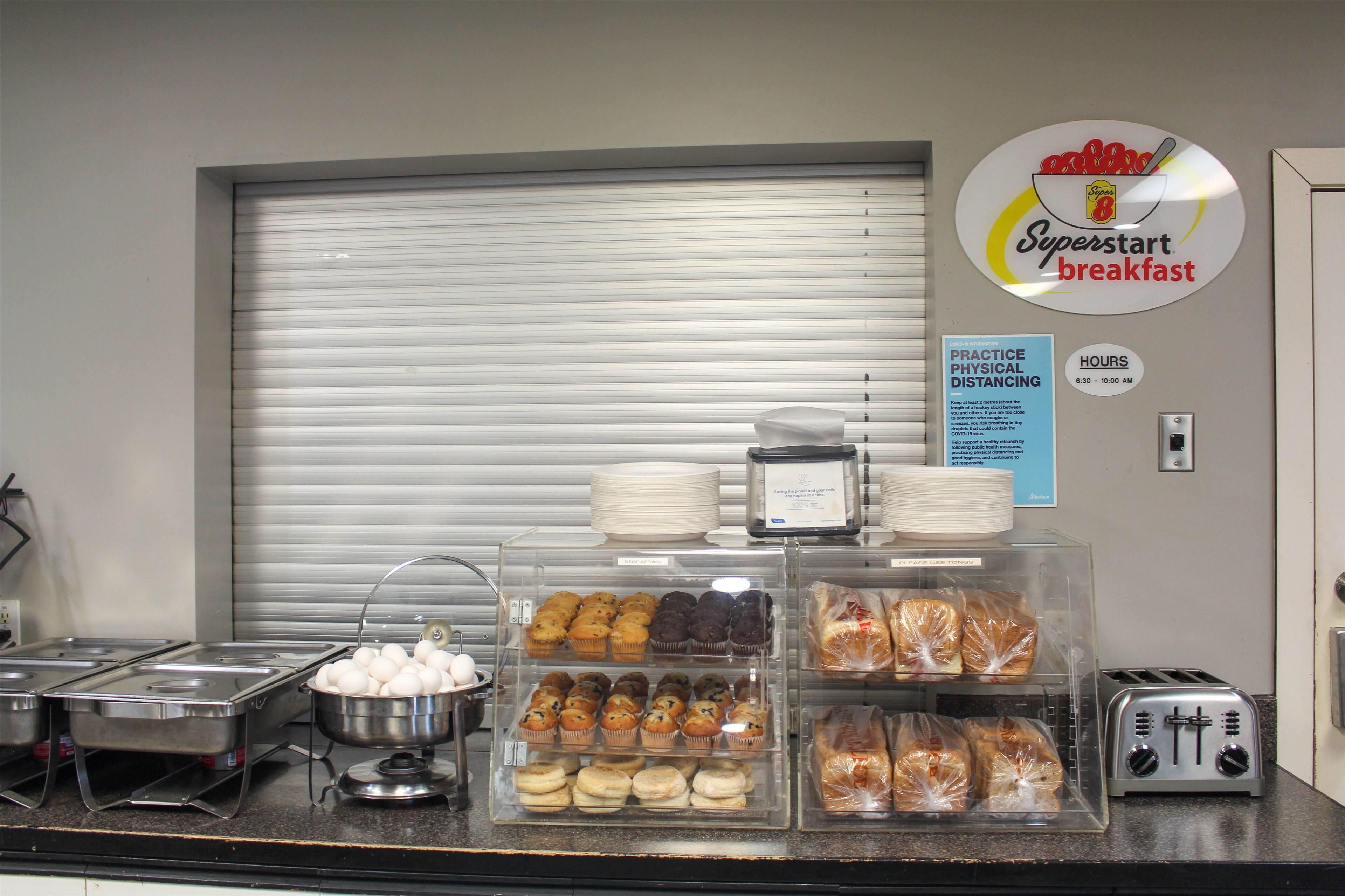 A breakfast buffet with various baked goods and pastries displayed in clear containers.