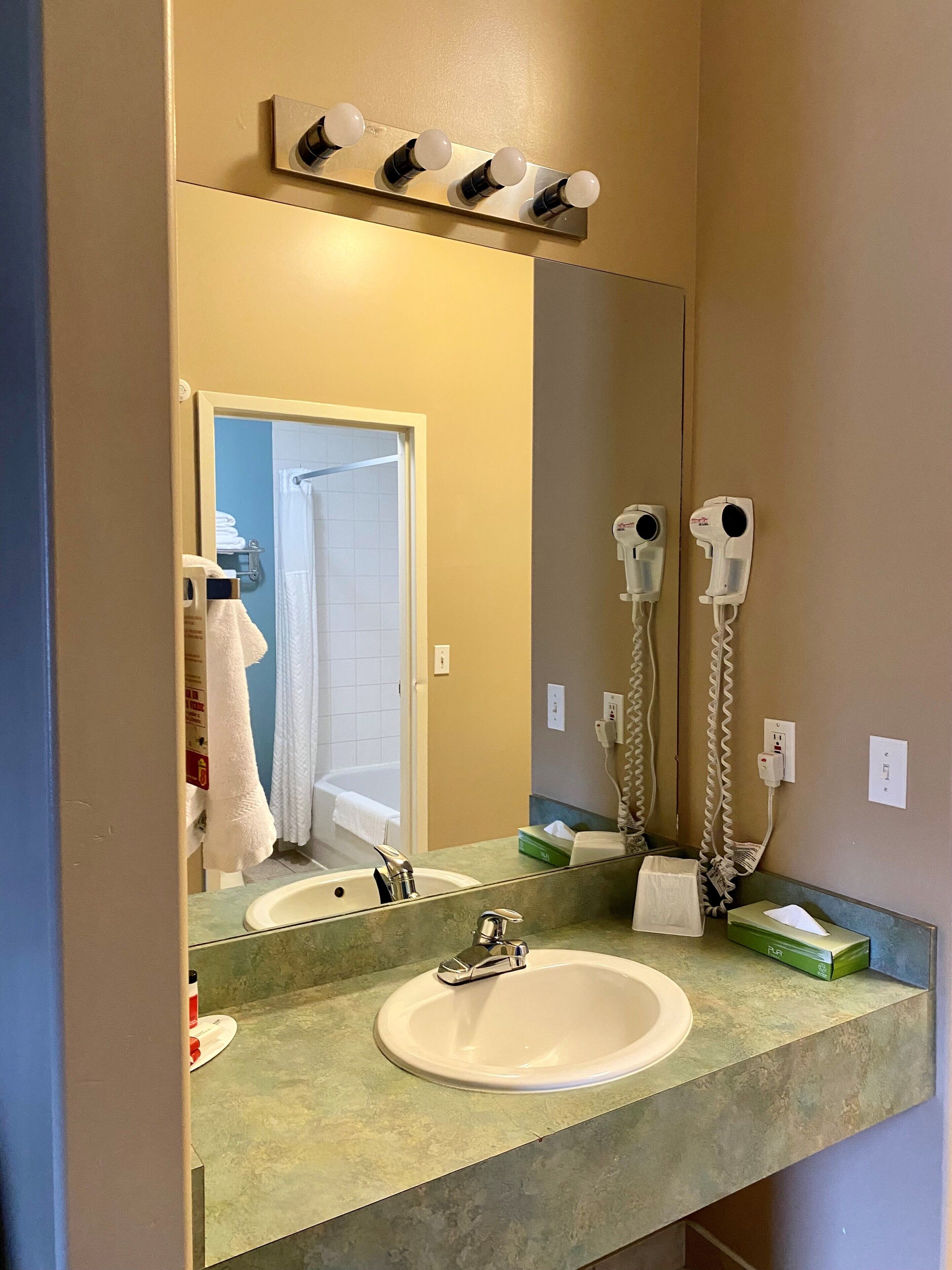 A bathroom with a sink, mirror, towel rack, and hairdryer.