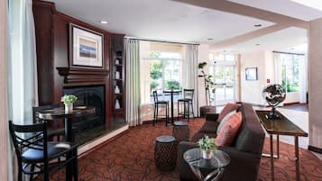 A hotel lobby with a fireplace, seating area, and large windows.