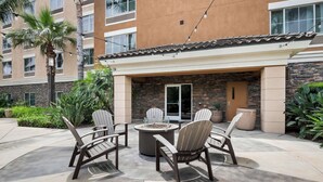 An outdoor patio with Adirondack chairs and a fire pit, surrounded by a stone wall and a building with multiple windows. - Best Western Ontario Mills Mall (Ontario)