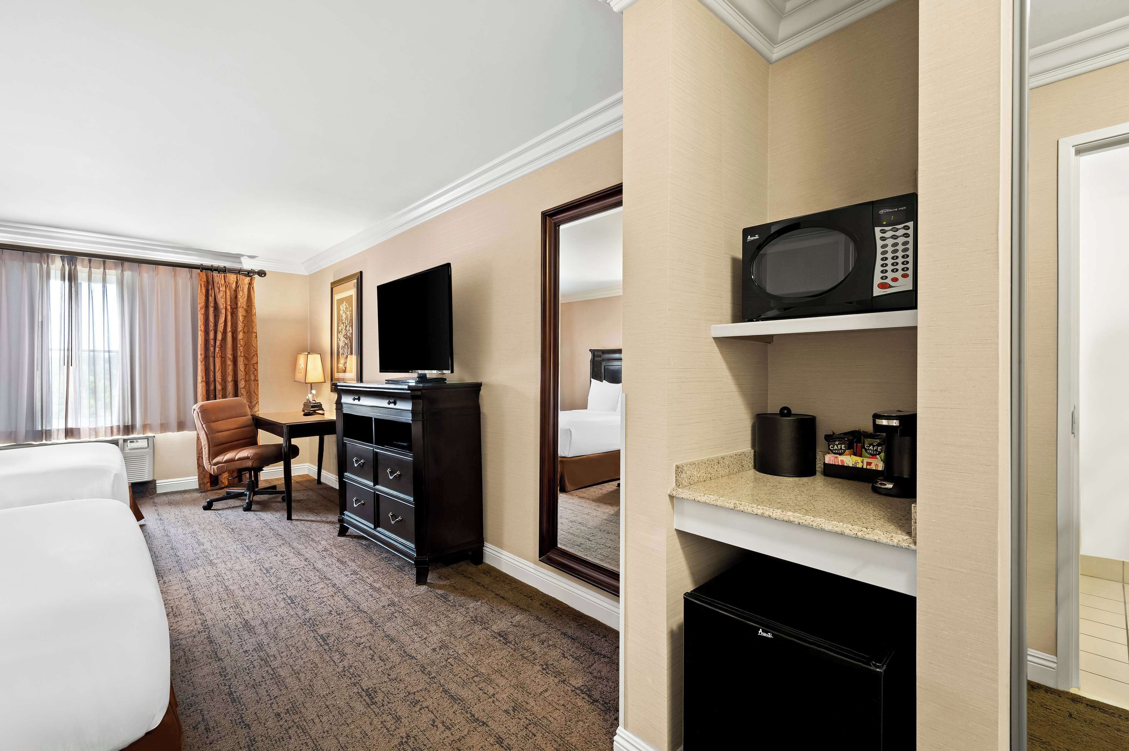 Ein Hotelzimmer mit Bett, Schreibtisch, Sessel, Fernseher, Mikrowelle und einer Kaffeemaschine.