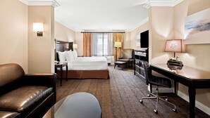 A hotel room with a bed, a desk, a chair, a sofa, a lamp, and a painting on the wall. - Best Western Ontario Mills Mall (Ontario)