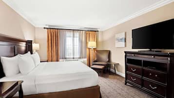 A hotel room with a large bed, a television, a desk, a chair, and a dresser.