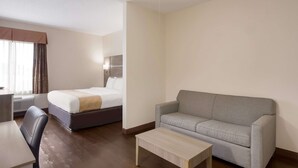 A hotel room with a bed, a sofa, a desk, and a ceiling fan.