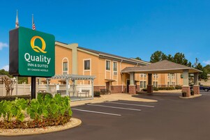 Edificio de Quality Inn & Suites, un hotel de Choice Hotels, con estacionamiento y un área de espera techada.