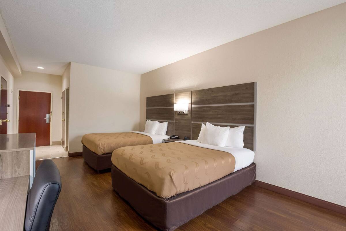 Ein Hotelzimmer mit zwei Betten, einem Schreibtisch und einem Stuhl.