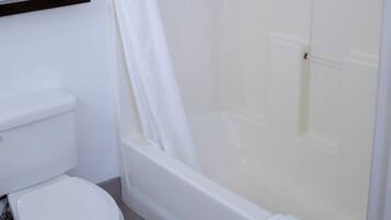 Une salle de bain équipée de toilettes, d’une baignoire et d’un rideau de douche.