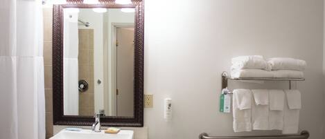 A bathroom with a white sink, a mirror with lights, a towel rack, and a hand dryer.