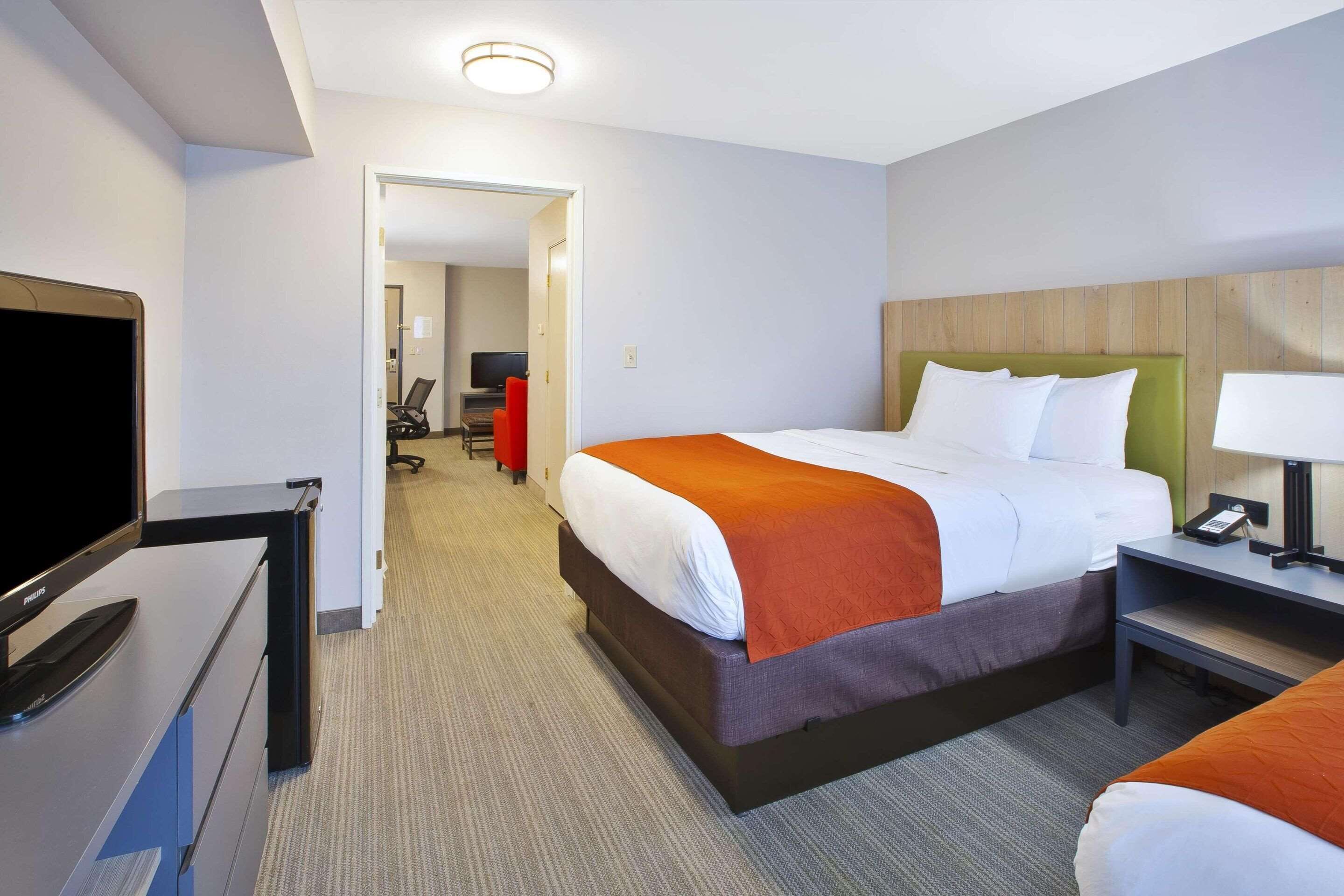 A hotel room with a bed, a desk with a television, and a chair.