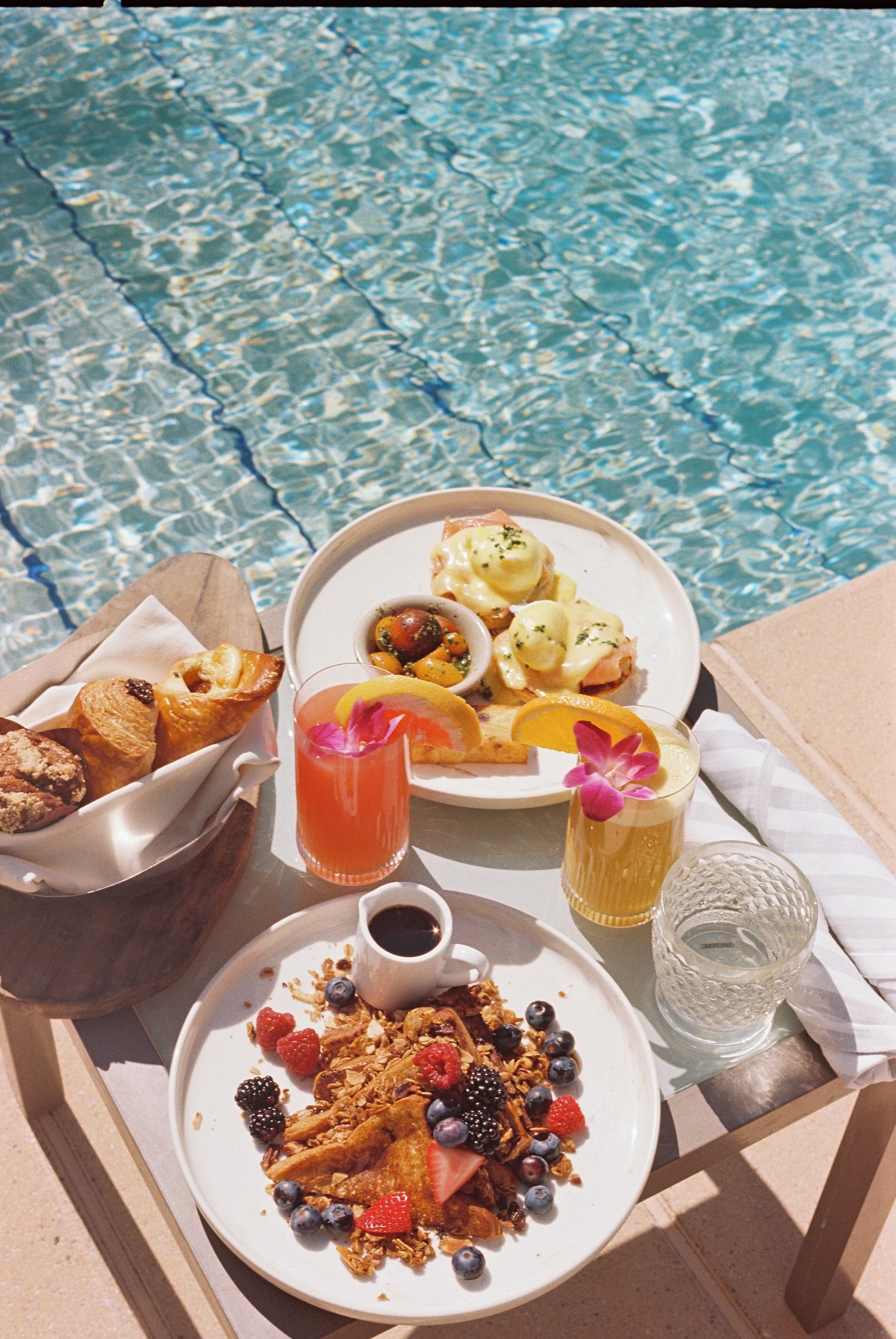 Ein Frühstücksbrett mit Pfannkuchen, Eiern und Toast neben einem Pool.