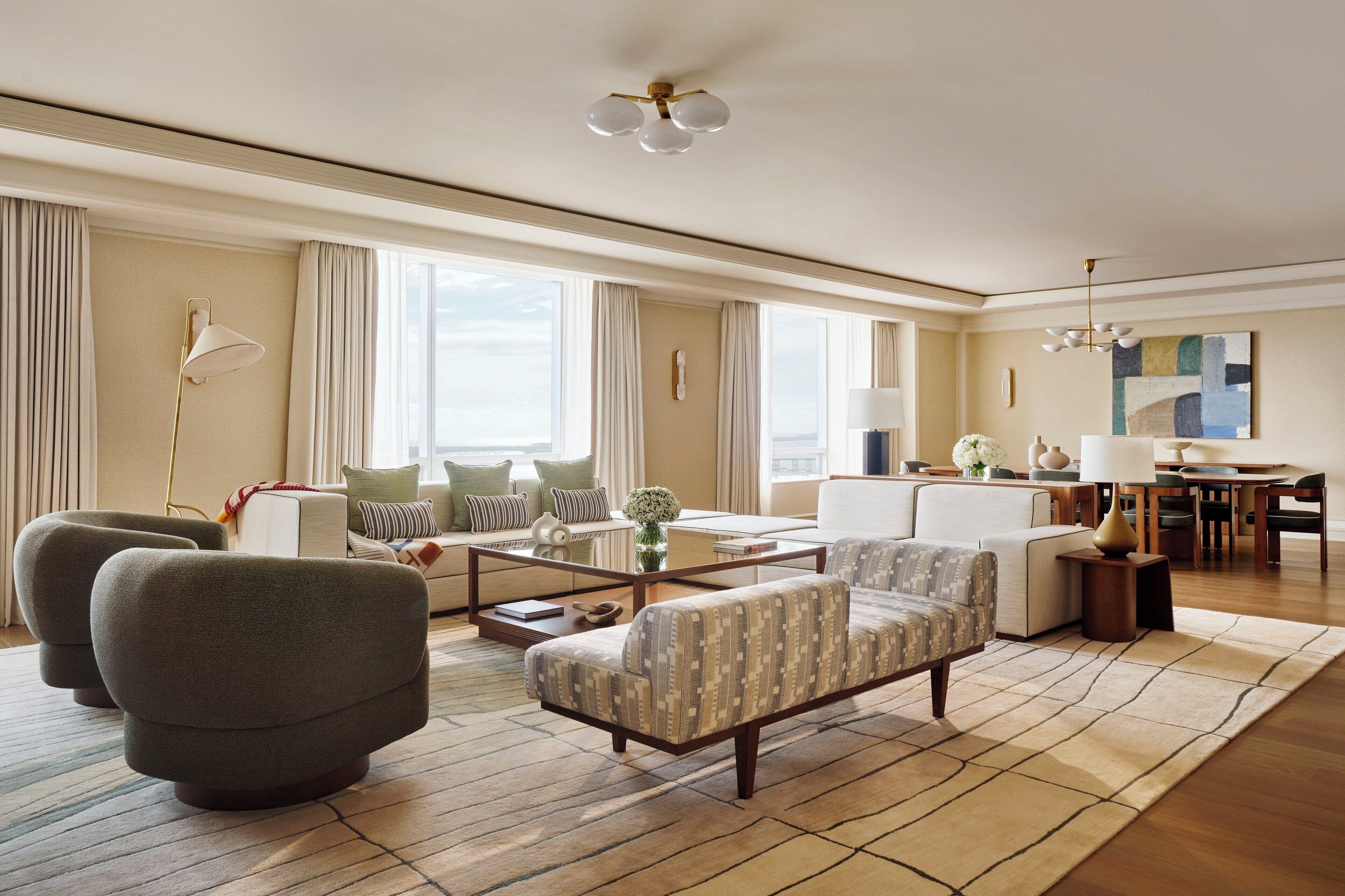A spacious living room with a large sofa, armchairs, a coffee table, and a dining area with a chandelier.