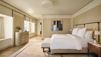 A modern bedroom with a large bed, a bedside table, a dresser, and a window with curtains.