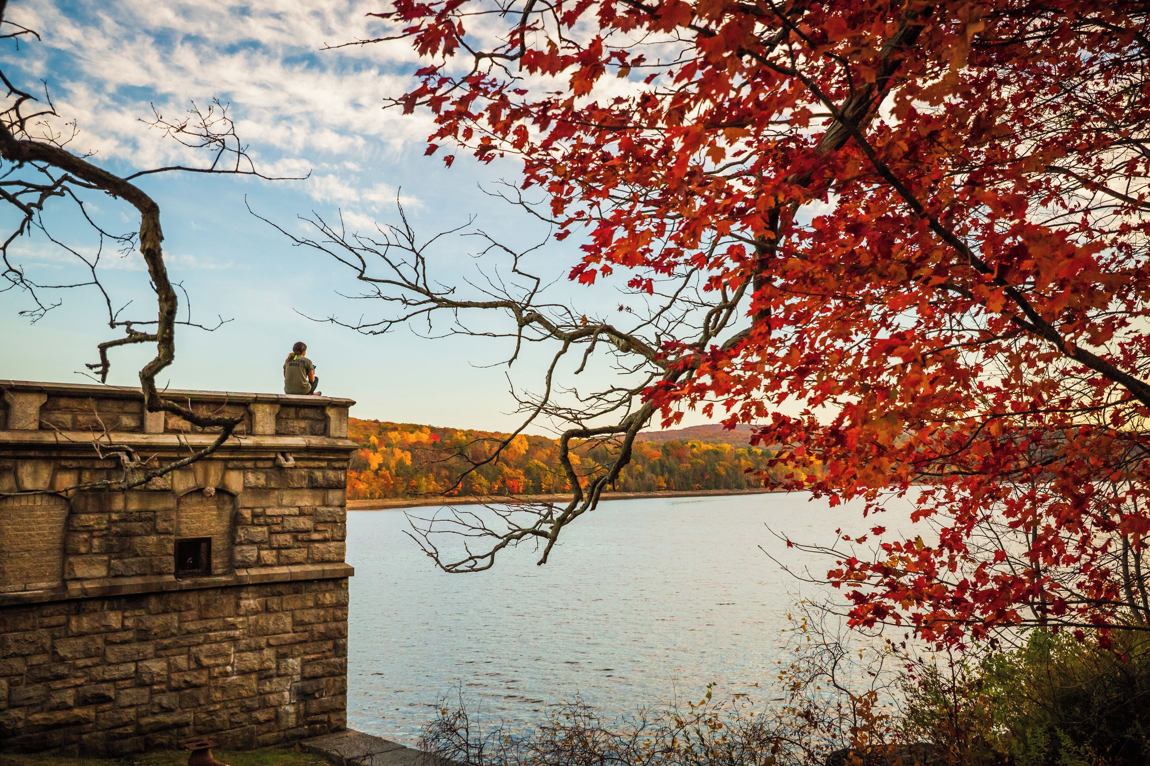A stone building with a view of a lake and autumn foliage.