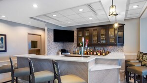 A modern kitchen with a bar area, marble countertops, and dark wooden cabinets. - Hilton Garden Inn Islip/MacArthur Airport (Ronkonkoma)