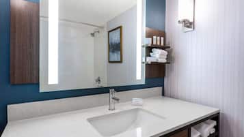 A modern bathroom with a large mirror, a sink, and a towel rack.