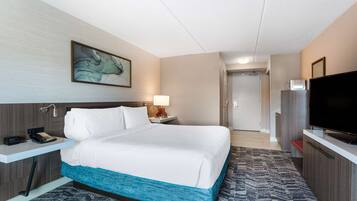 Een hotelkamer met een bed, een bureau met telefoon, een televisie en een schilderij aan de muur.