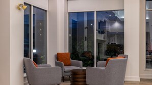 A modern living room with grey armchairs and a round wooden coffee table. - Hilton Garden Inn Auburn Lewiston Riverwatch (Auburn)