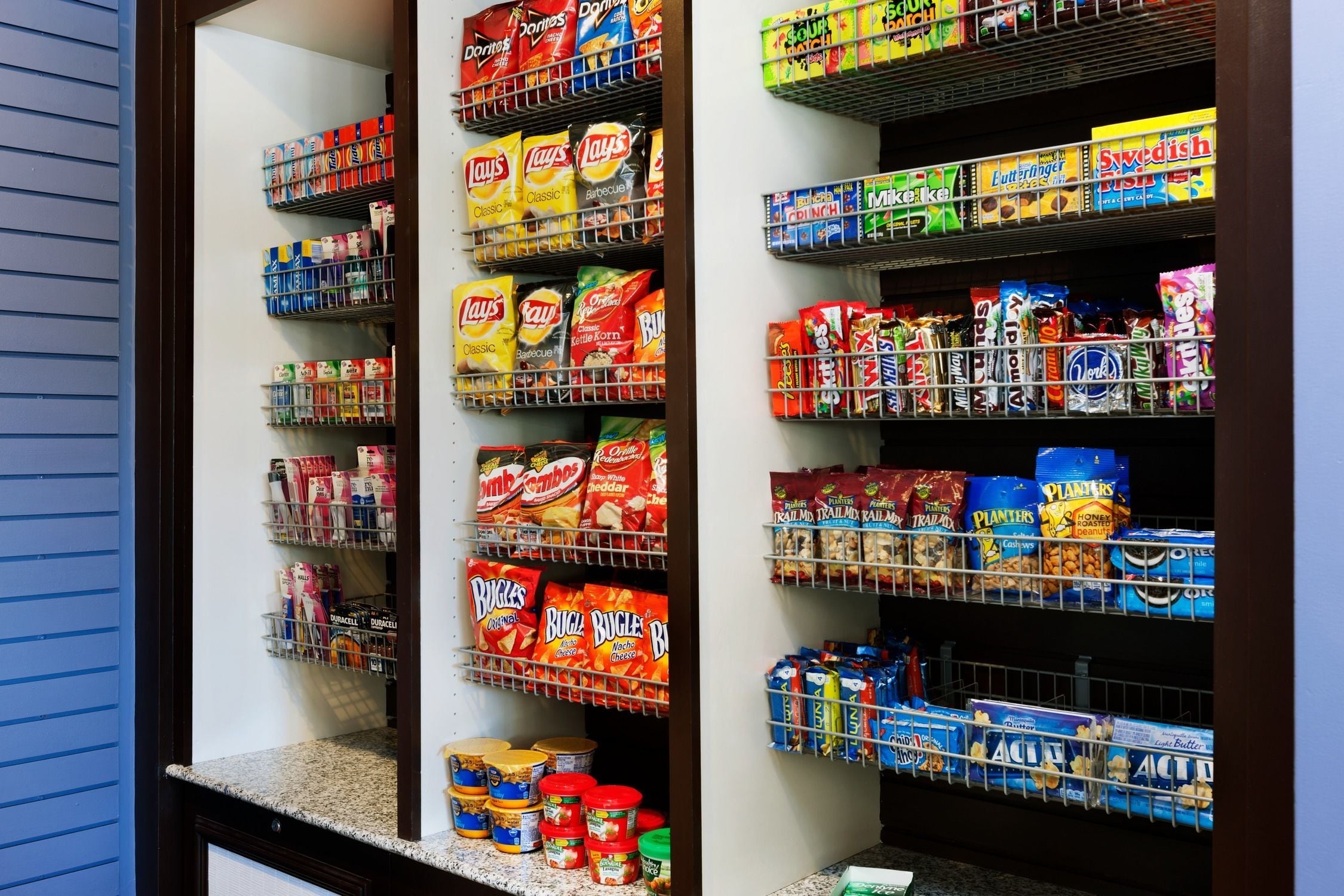 Una dispensa con ripiani pieni di snack e condimenti di vario tipo.