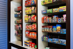 A pantry with shelves stocked with various snacks and condiments. - Hilton Garden Inn Auburn Lewiston Riverwatch (Auburn)
