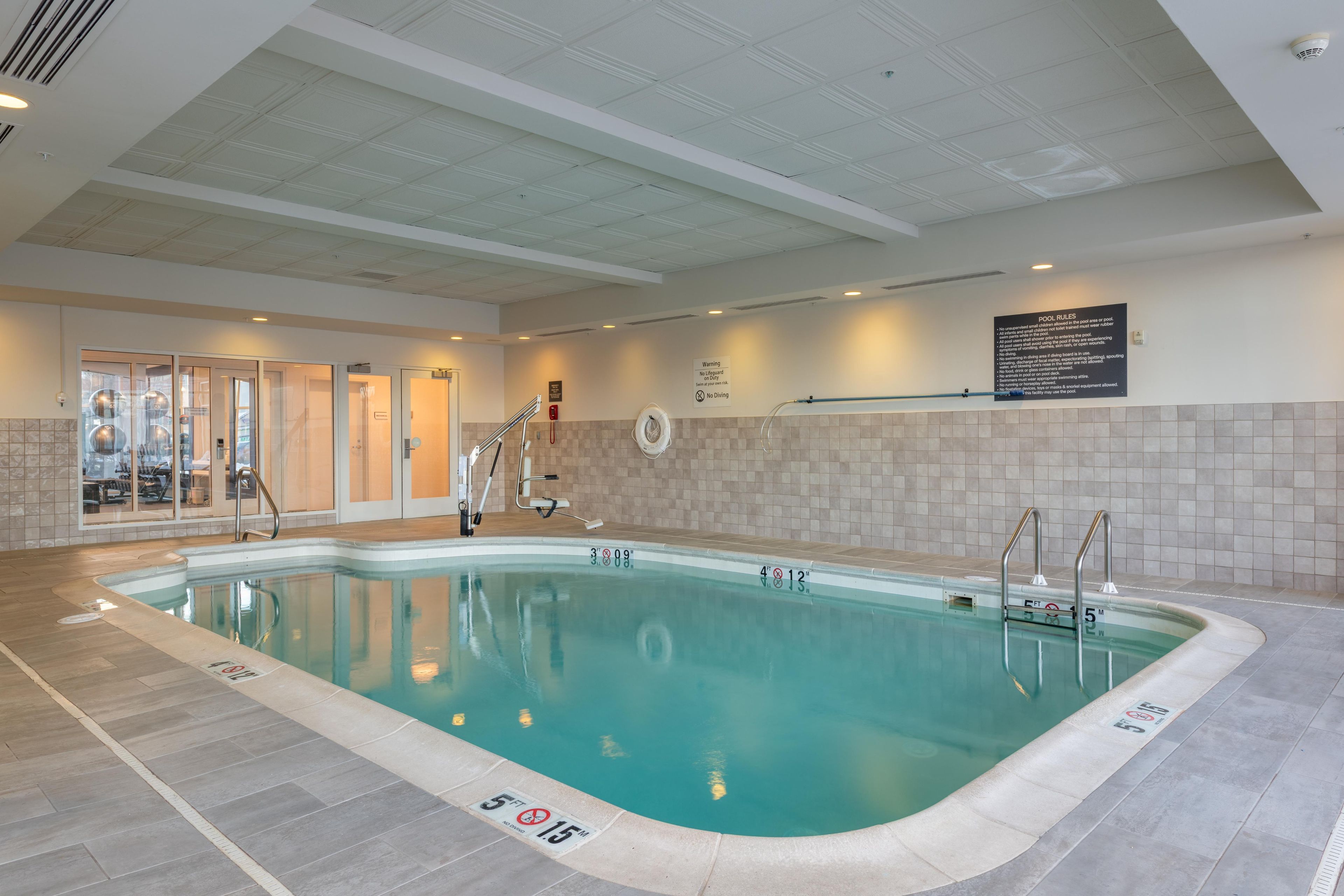 An indoor swimming pool with clear water, marked depth lines, and a 'No Diving' sign.