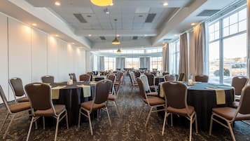 Une salle de conférence dotée de plusieurs tables et chaises, de grandes fenêtres et d’un éclairage au plafond.