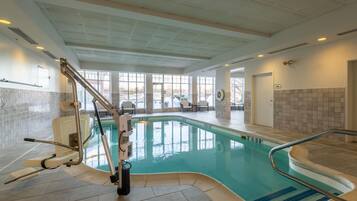An indoor swimming pool with a sunroof, a changing room, and a seating area with chairs.