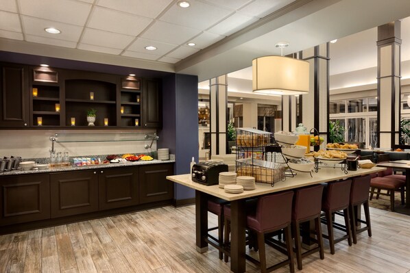 A modern kitchen with dark cabinetry, a central island with bar stools, and a large pendant light.