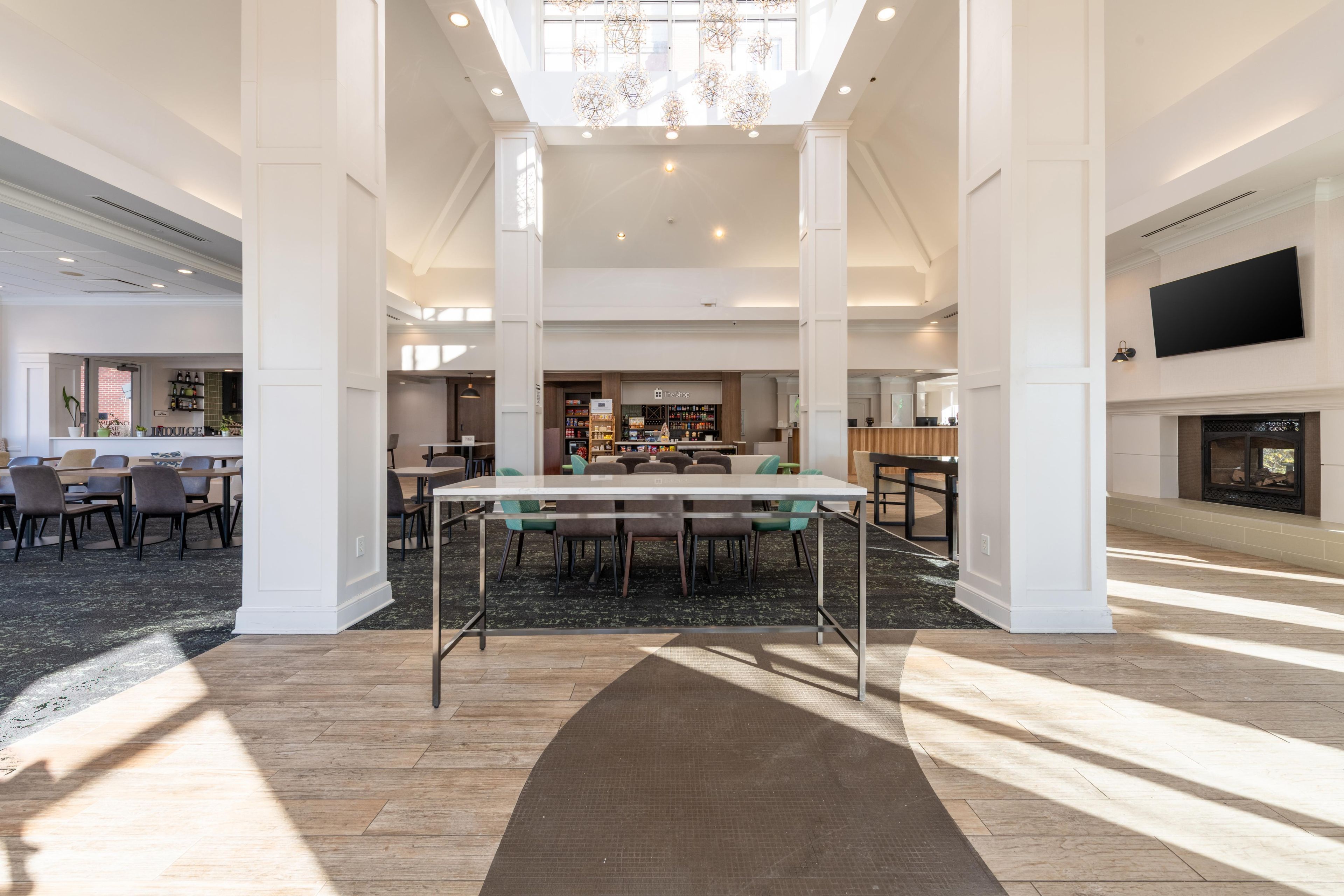 Un hall d’entrée spacieux avec un plafond haut, une table centrale et une cheminée.