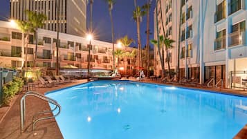 Una piscina al aire libre, sillones reclinables de piscina