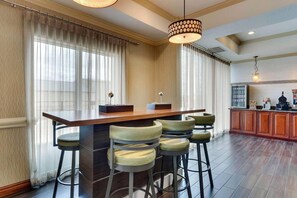 A bar area with a wooden counter, bar stools, and pendant lighting.