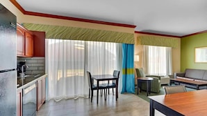 A modern kitchen with a built-in stove, a dining area with a table and chairs, and a living area with a sofa and a small table. - Comfort Inn & Suites Waco Woodway (Waco)