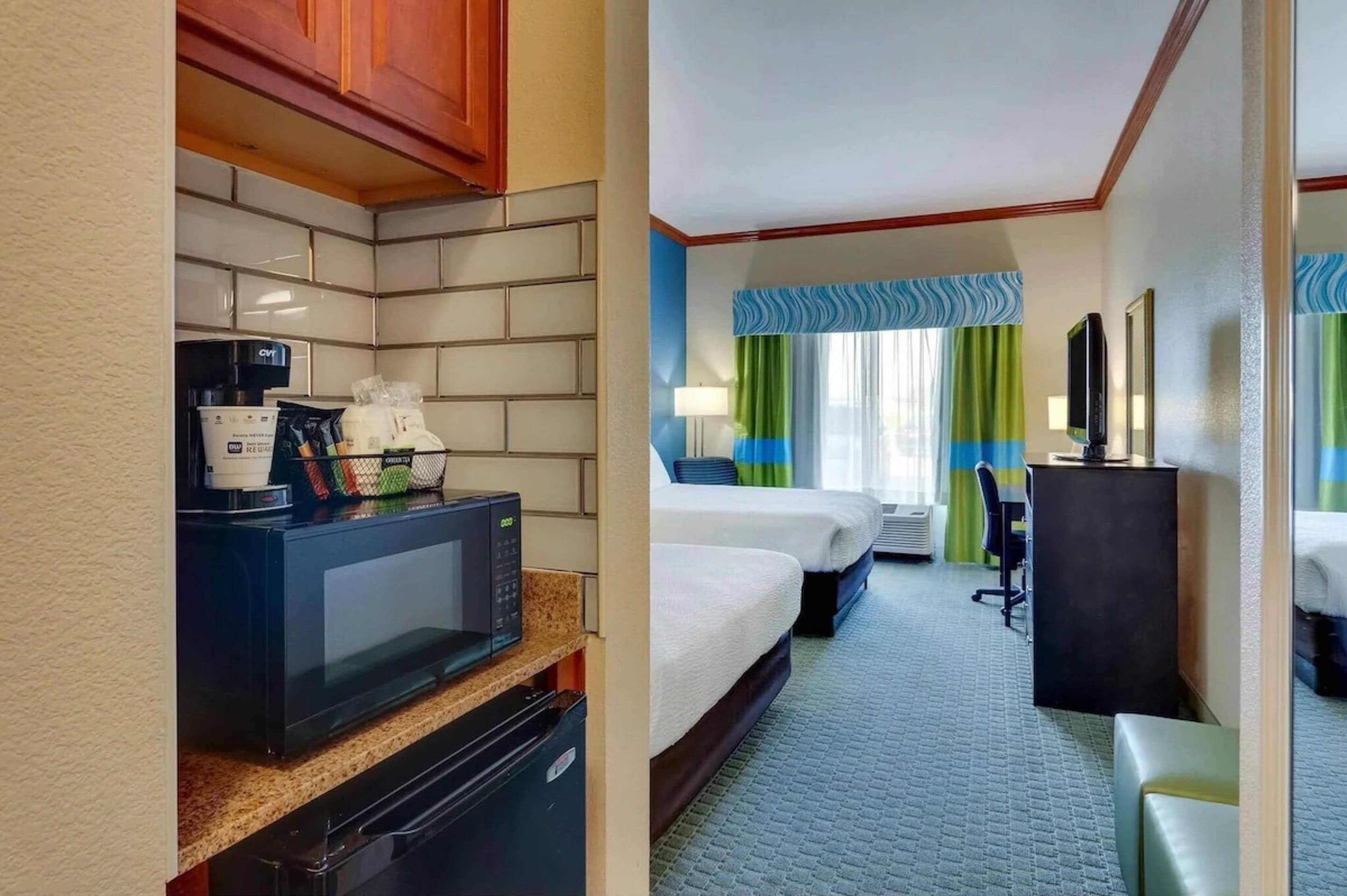 Une chambre d’hôtel équipée d’une kitchenette, de deux lits, d’un bureau et d’une télévision.