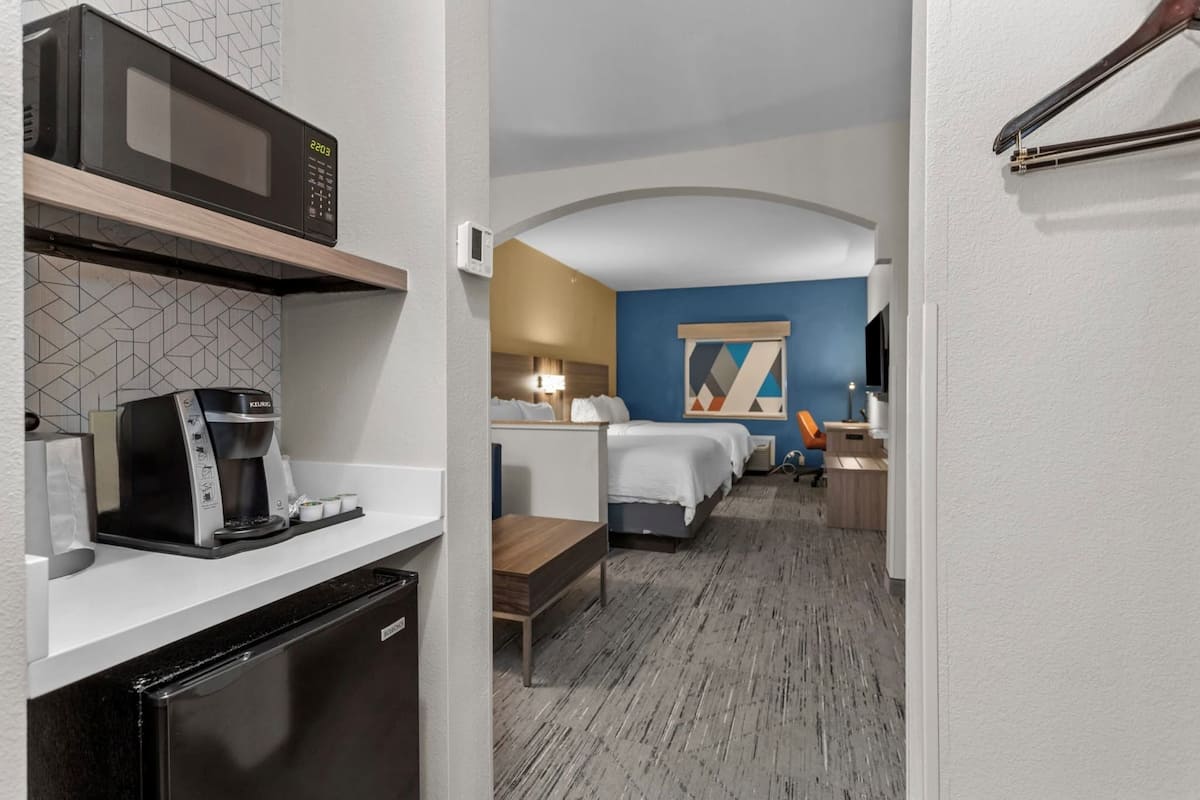 Une chambre d’hôtel équipée d’une kitchenette, d’un lit, d’un bureau et d’une salle de bain.