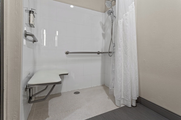 A bathroom with a shower, a toilet, and a grab bar.