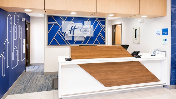 A reception desk with a blue and white geometric wall design, a wooden accent panel, and a sign for Holiday Inn Express & Suites. - Holiday Inn Express & Suites Yankton by IHG (Yankton)
