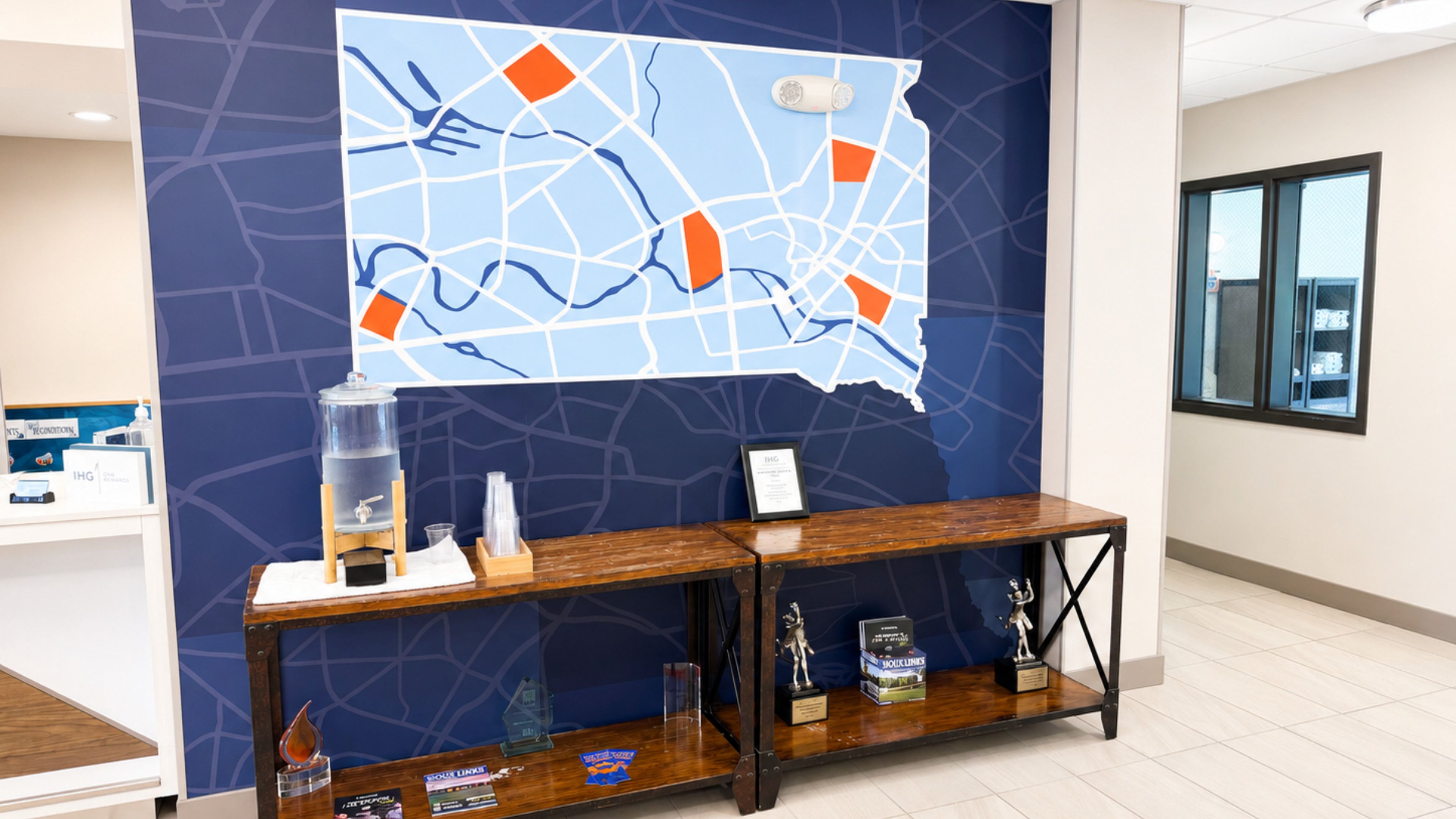 A reception area with a map on the wall, a water dispenser, and a display of awards on a wooden console.
