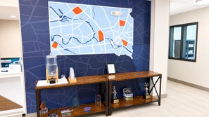 Een receptie met een kaart aan de muur, een waterdispenser en een vitrine met onderscheidingen op een houten console.