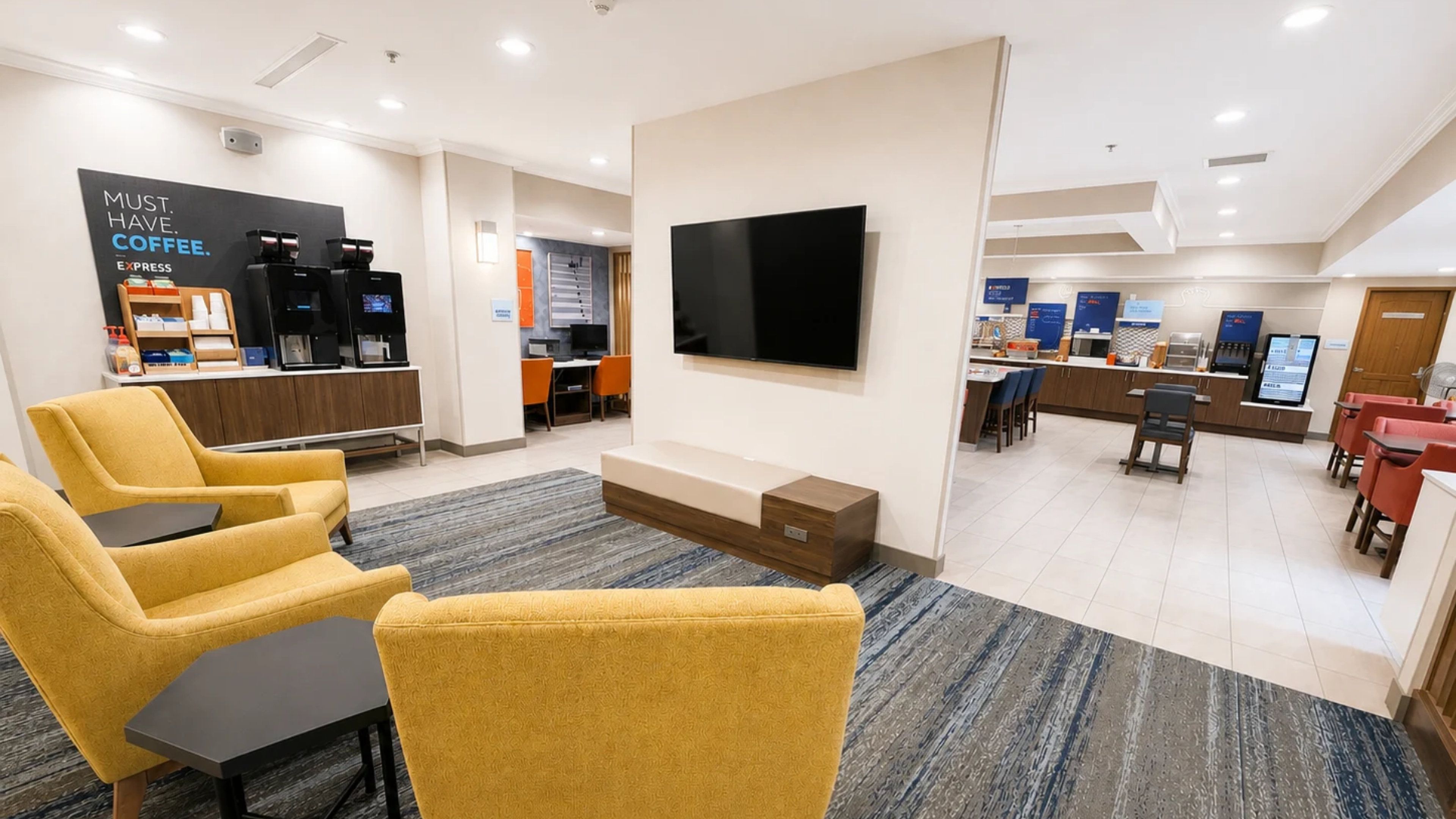 Recepció d'hotel moderna amb seients, un racó de cafè, televisió i zona de dinar.