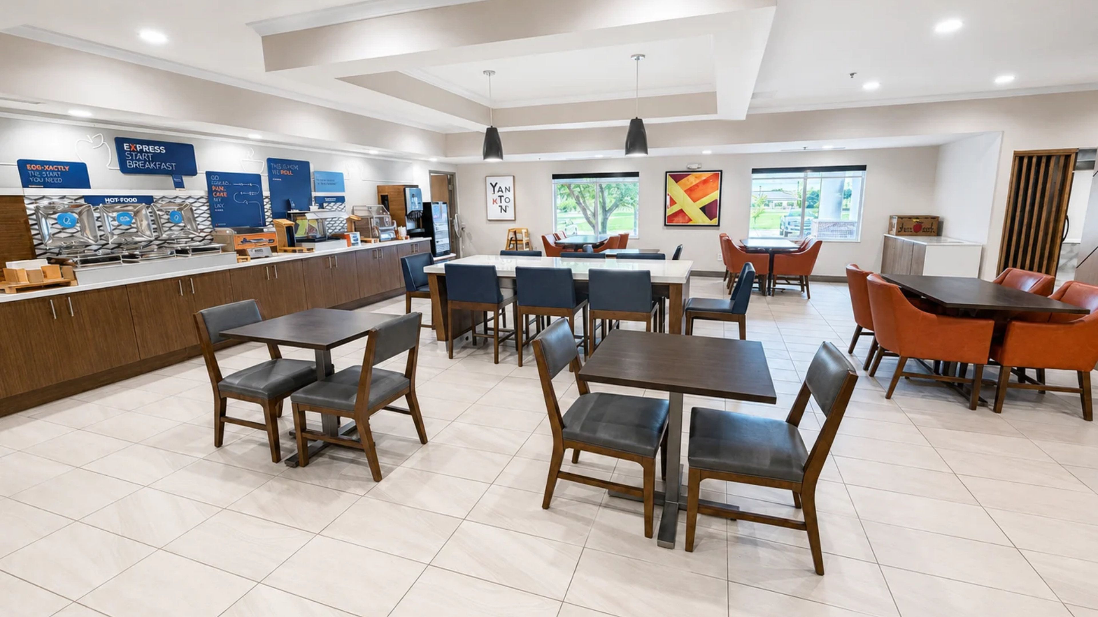 A modern restaurant with a counter, multiple tables, and chairs.
