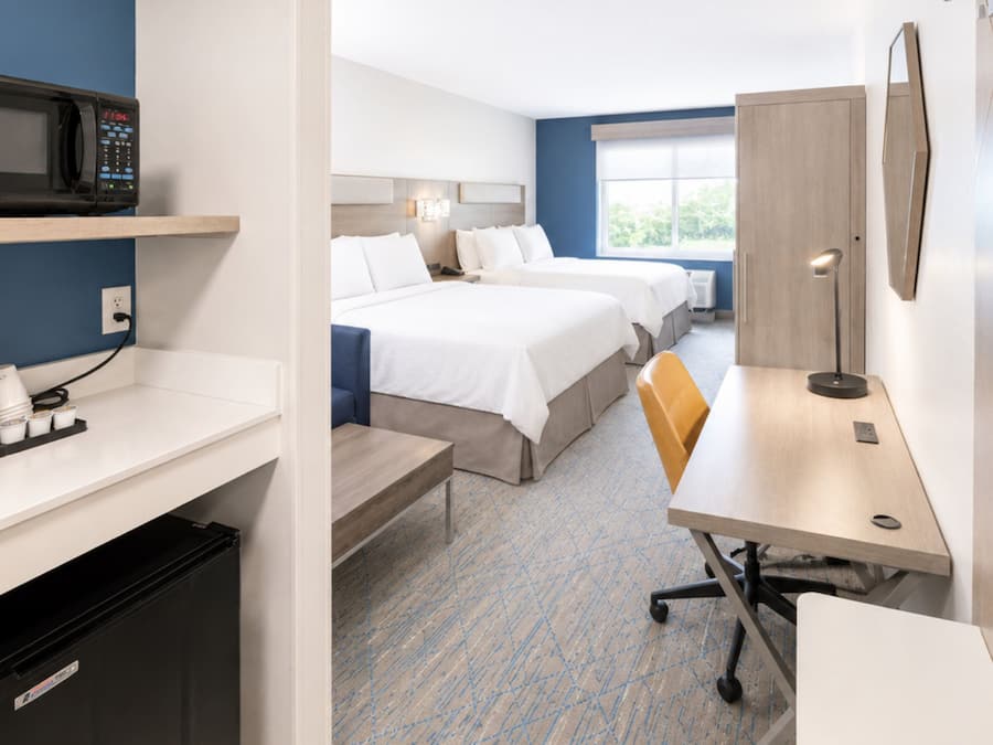 Una habitación de hotel con kitchenette, cama, escritorio y silla.