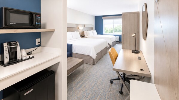 Une chambre d’hôtel équipée d’une kitchenette, d’un lit, d’un bureau et d’une chaise.
