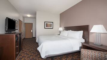 Habitación de hotel con cama, dos lámparas de noche, televisor sobre un mueble de madera y alfombra estampada.