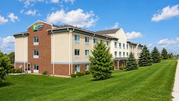 Un hôtel Holiday Inn Express avec une façade en briques, de nombreuses fenêtres et une pelouse bien entretenue.