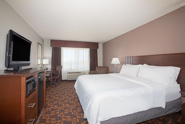 A hotel room with a bed, a desk with a television, a chair, a lamp, and a window with curtains. - Holiday Inn Express & Suites Yankton by IHG (Yankton)
